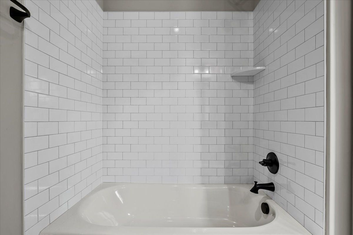 A bathroom with white brick walls and a bathtub