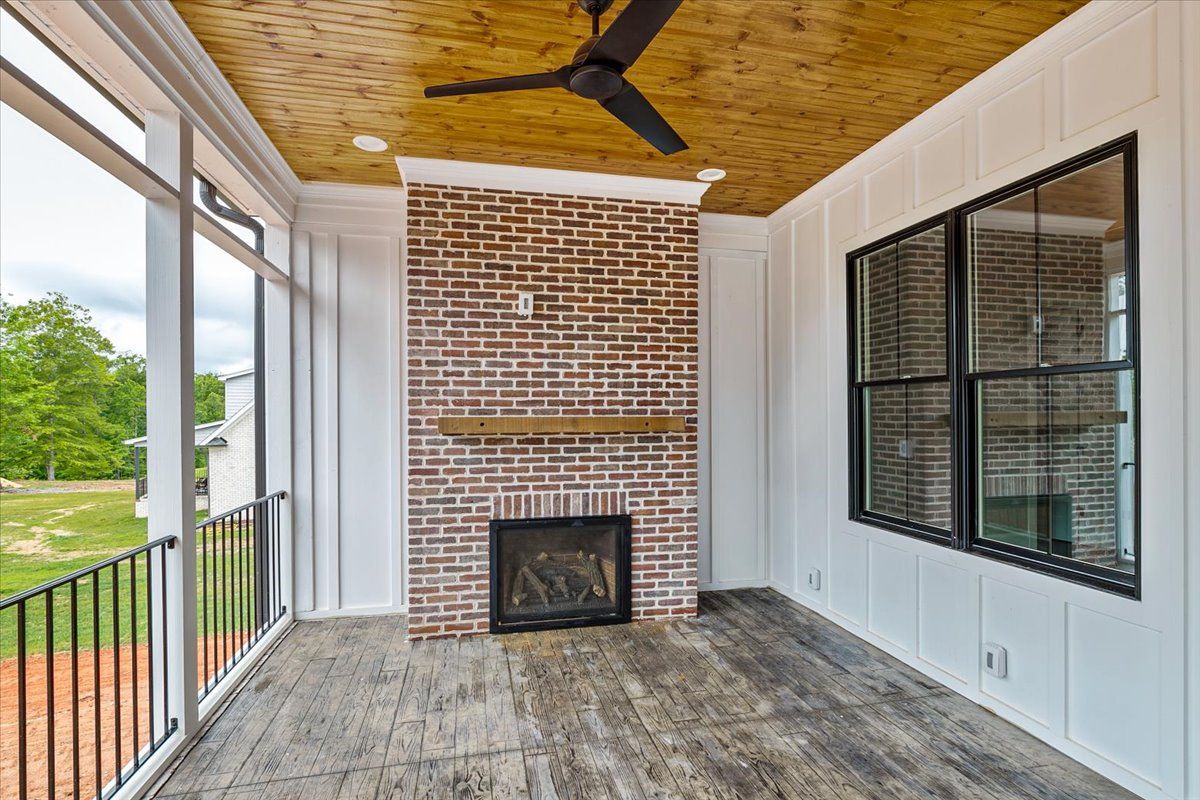 A porch with a fireplace and a ceiling fan