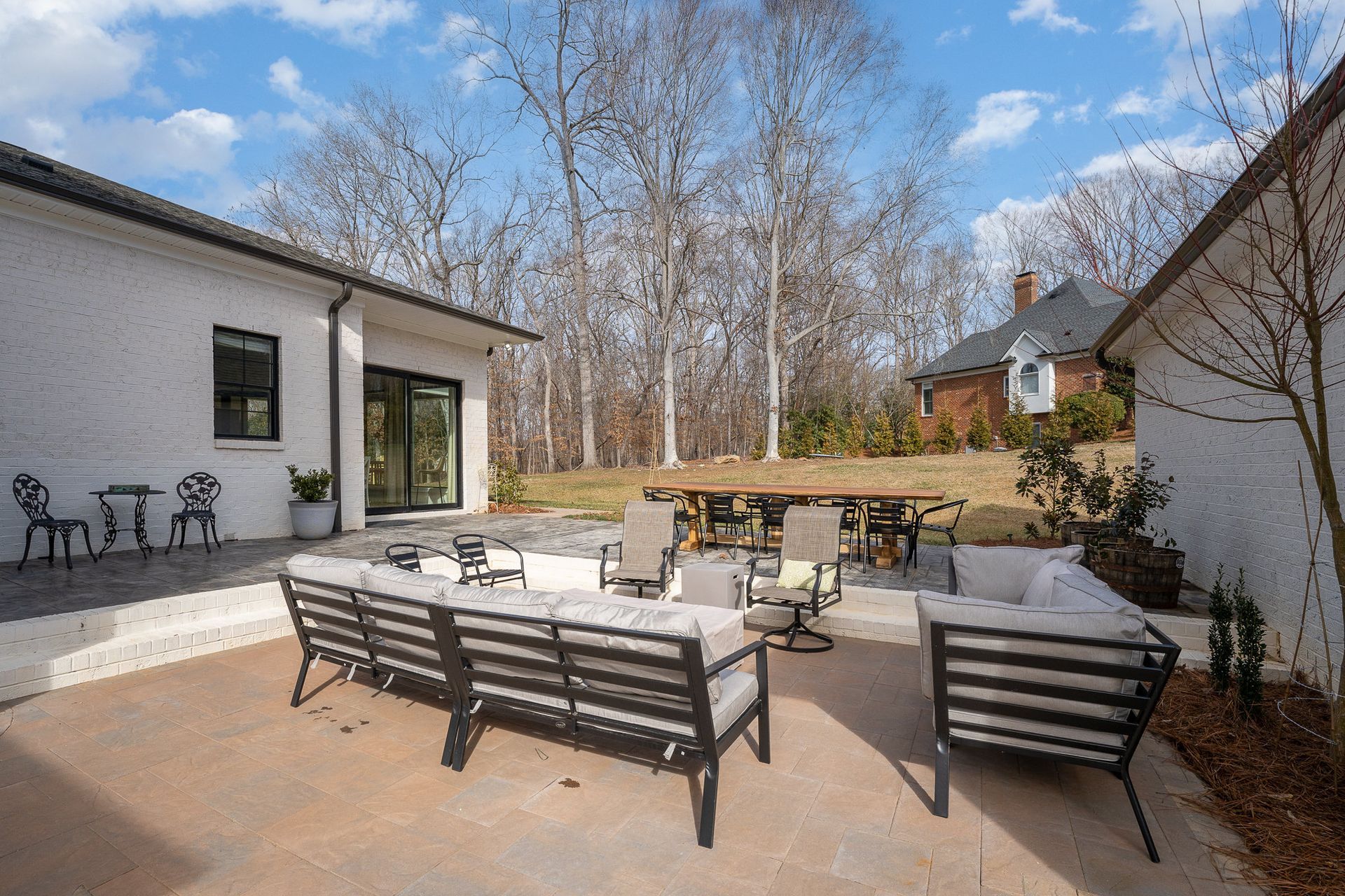 A patio with a couch and chairs in front of a house