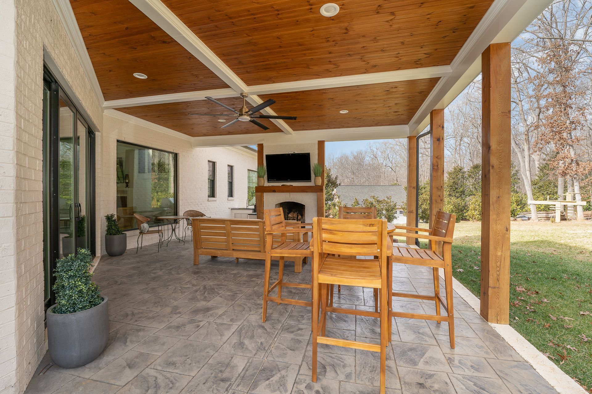 A large covered patio with a table and chairs and a fireplace