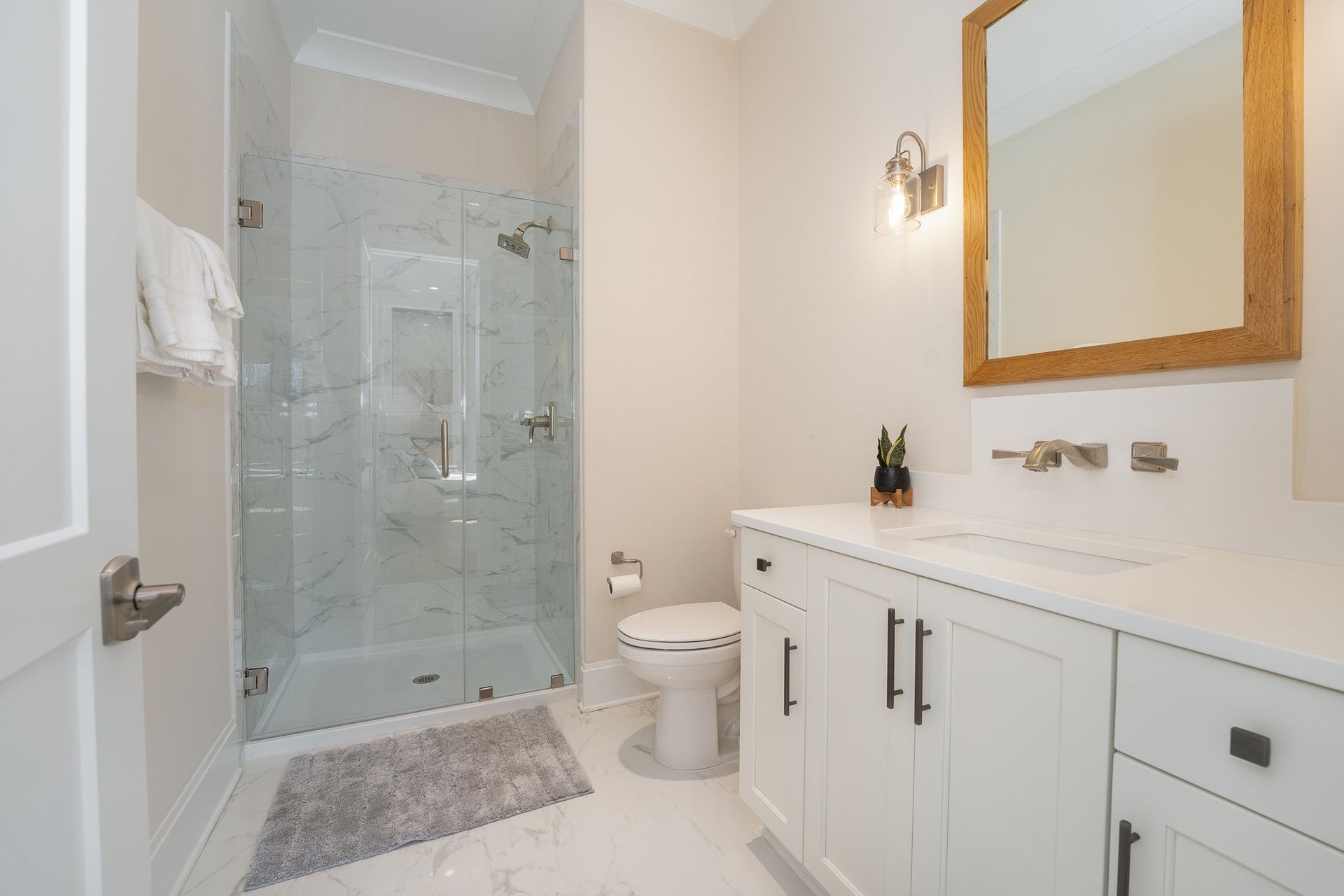 A bathroom with a toilet, sink, mirror, and shower