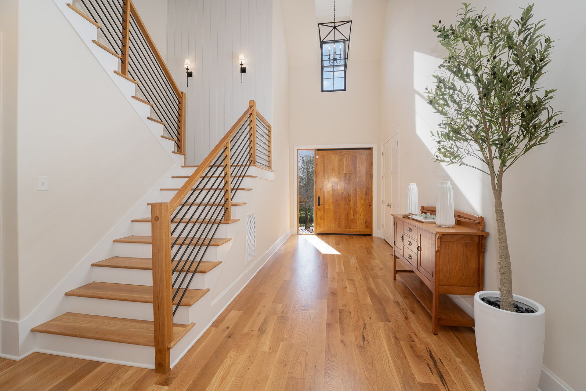 A hallway with stairs and a potted plant