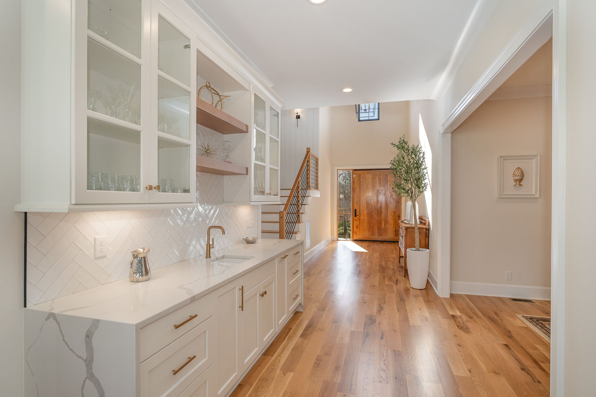 A kitchen with white cabinets and hardwood floors in a house