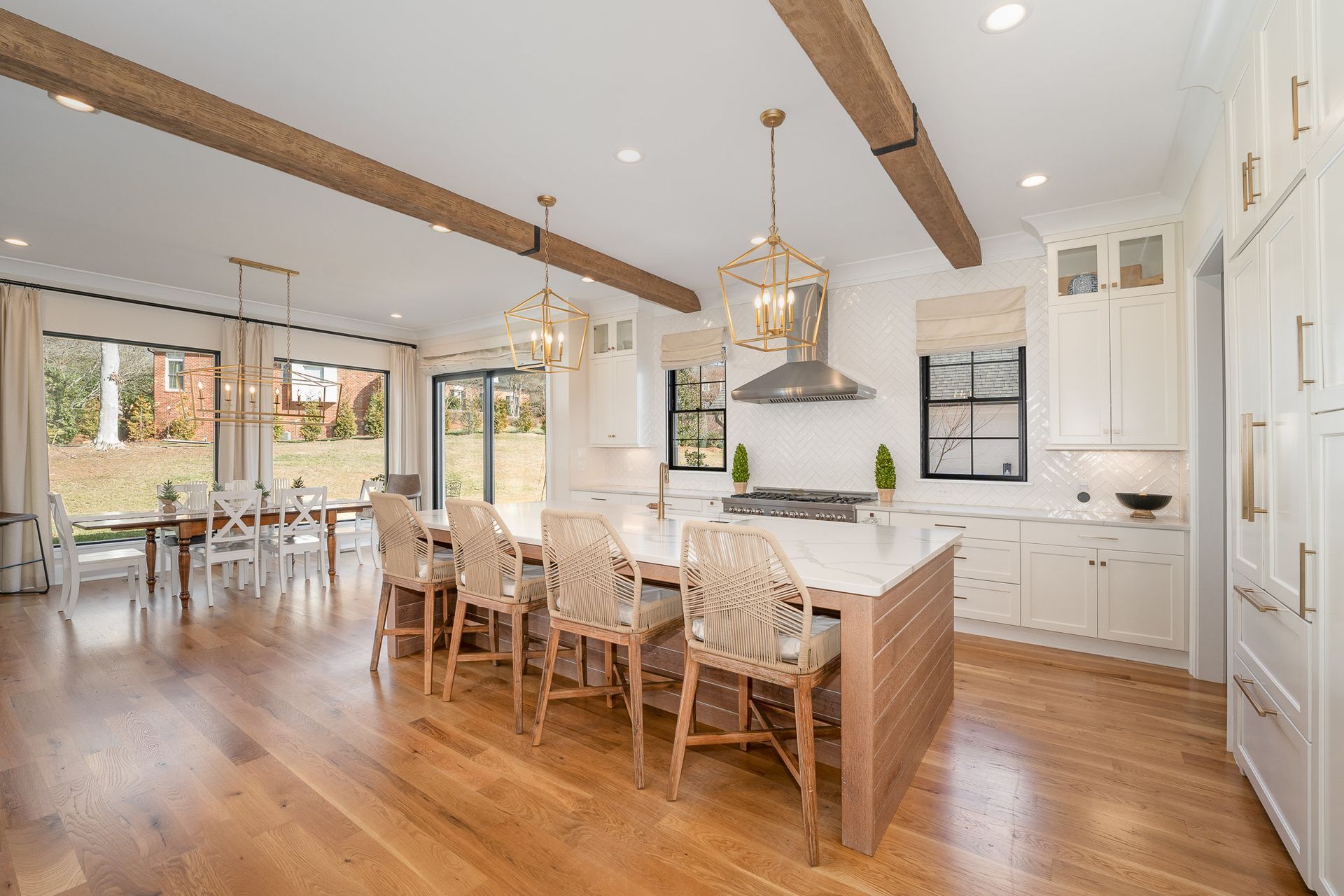 A kitchen with white cabinets, wooden floors, and a large island with chairs