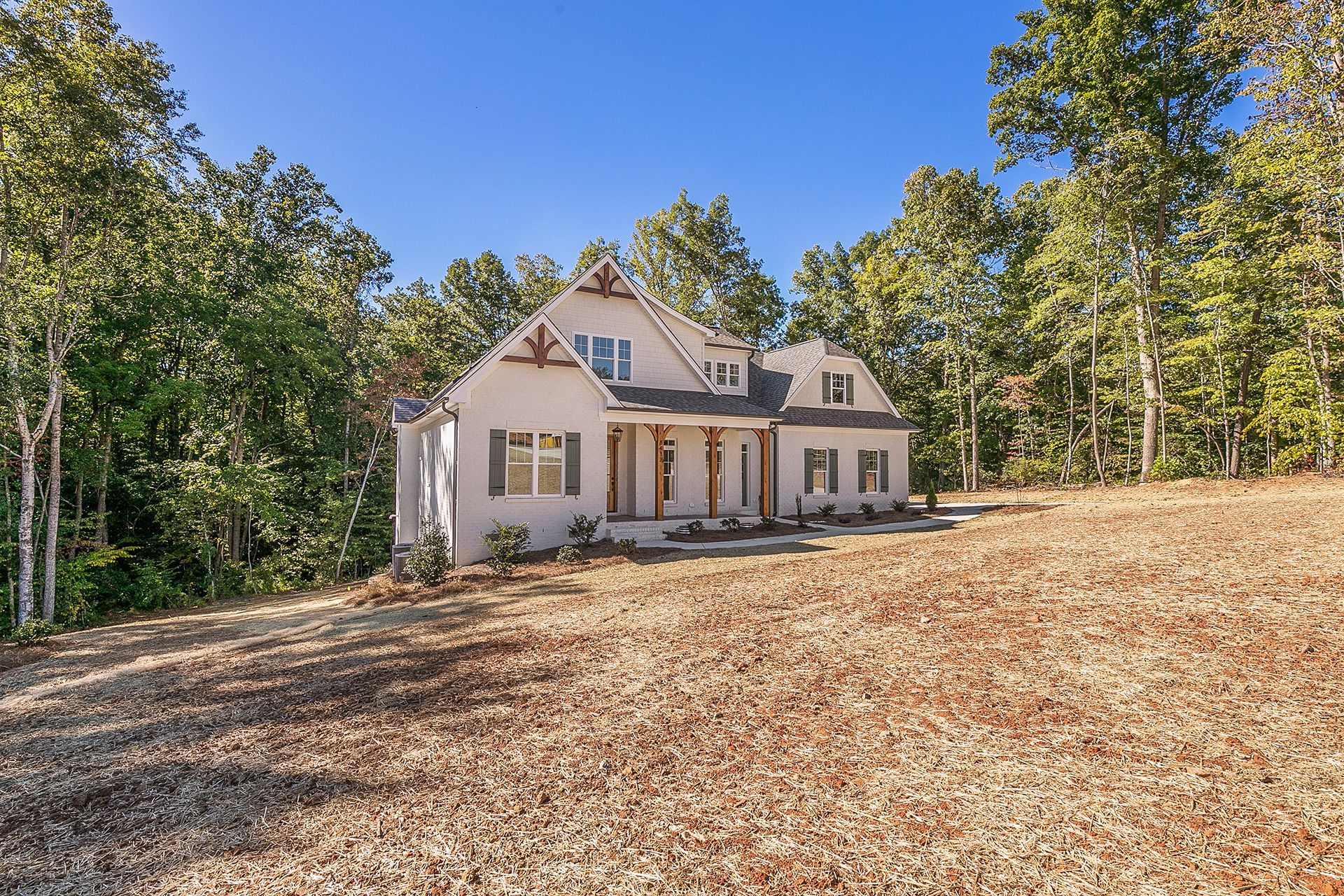 A large white house on top of a hill surrounded by trees