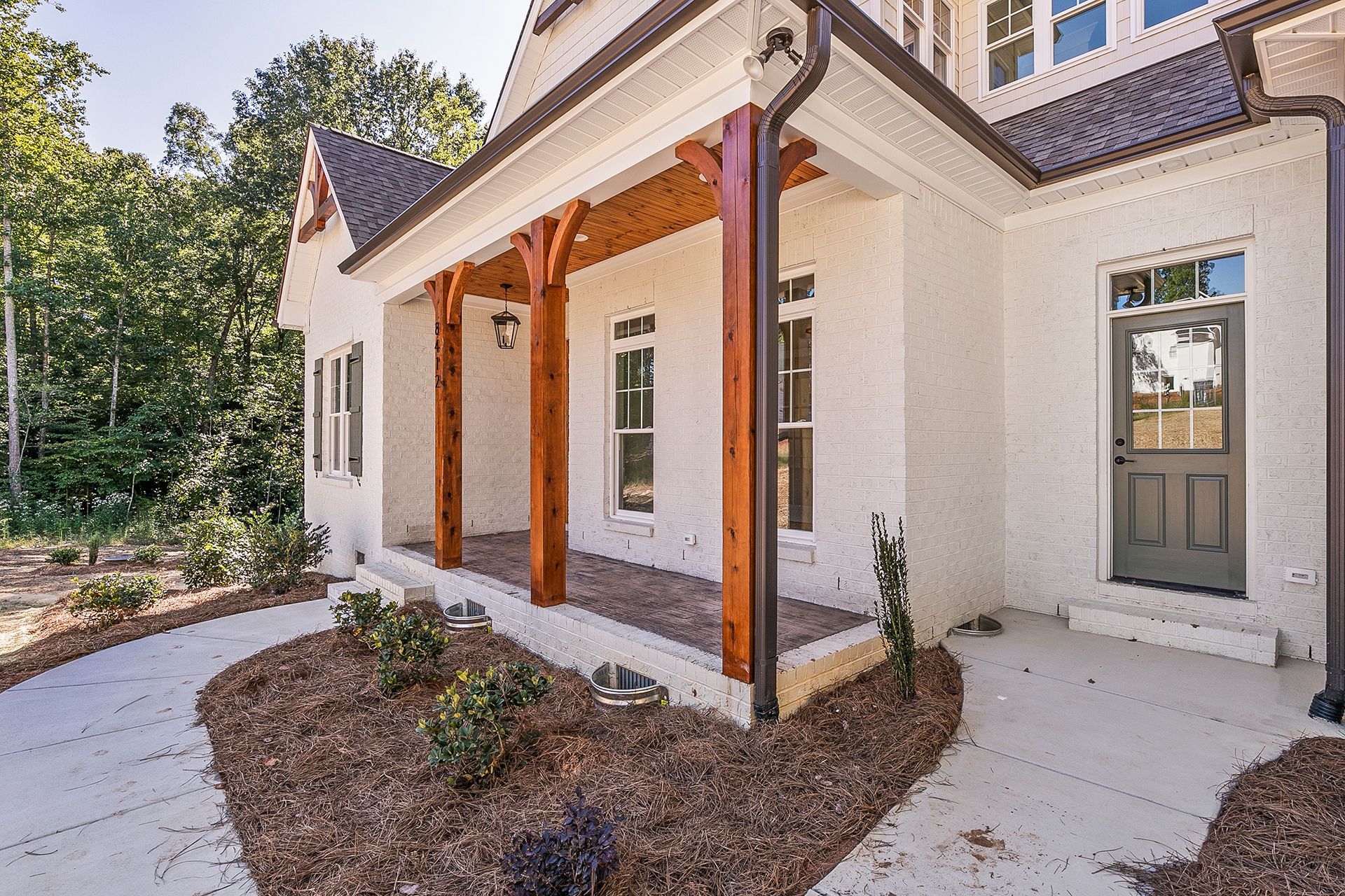 A white house with a porch wooden pillars
