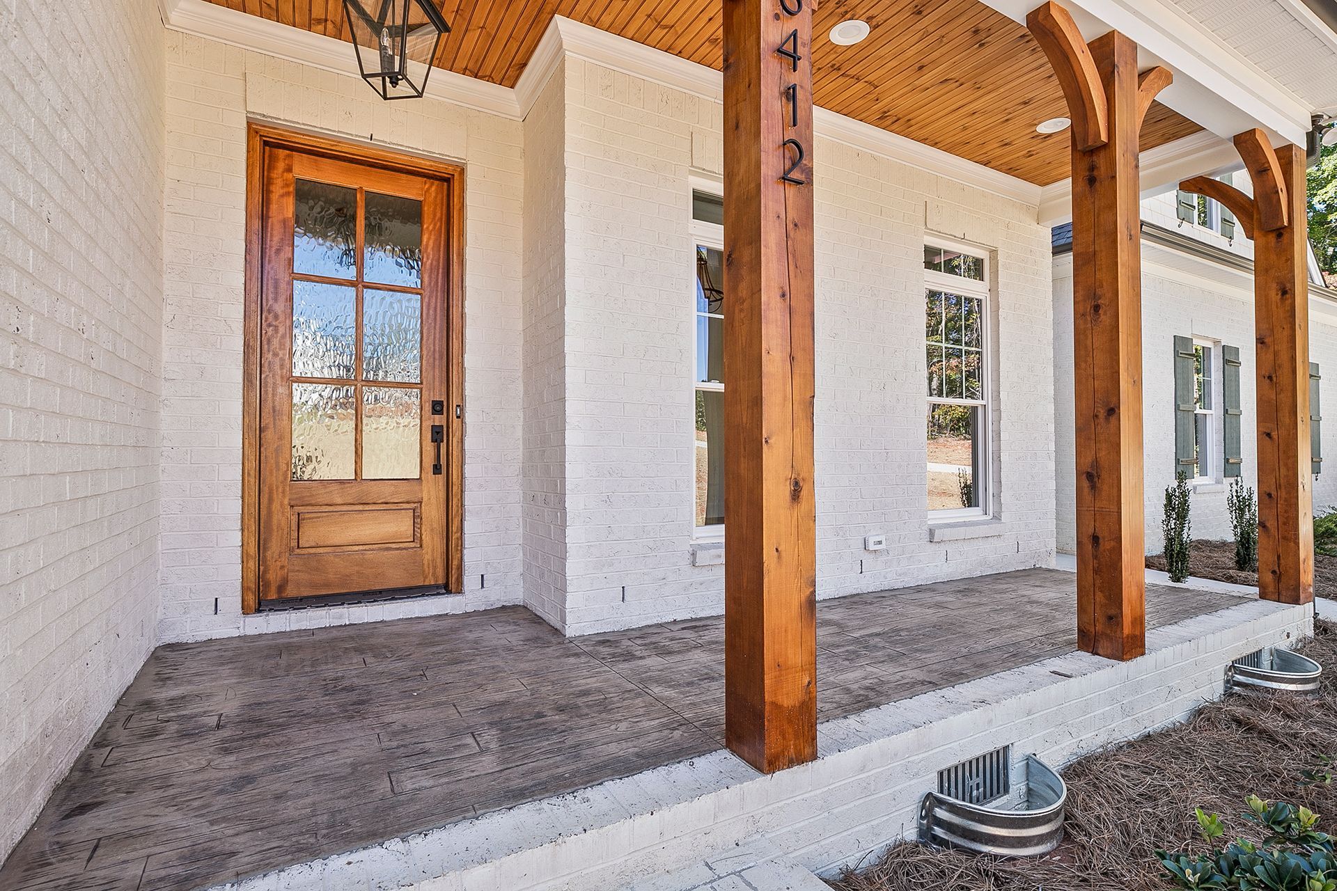 A white brick house with wooden pillars and a door