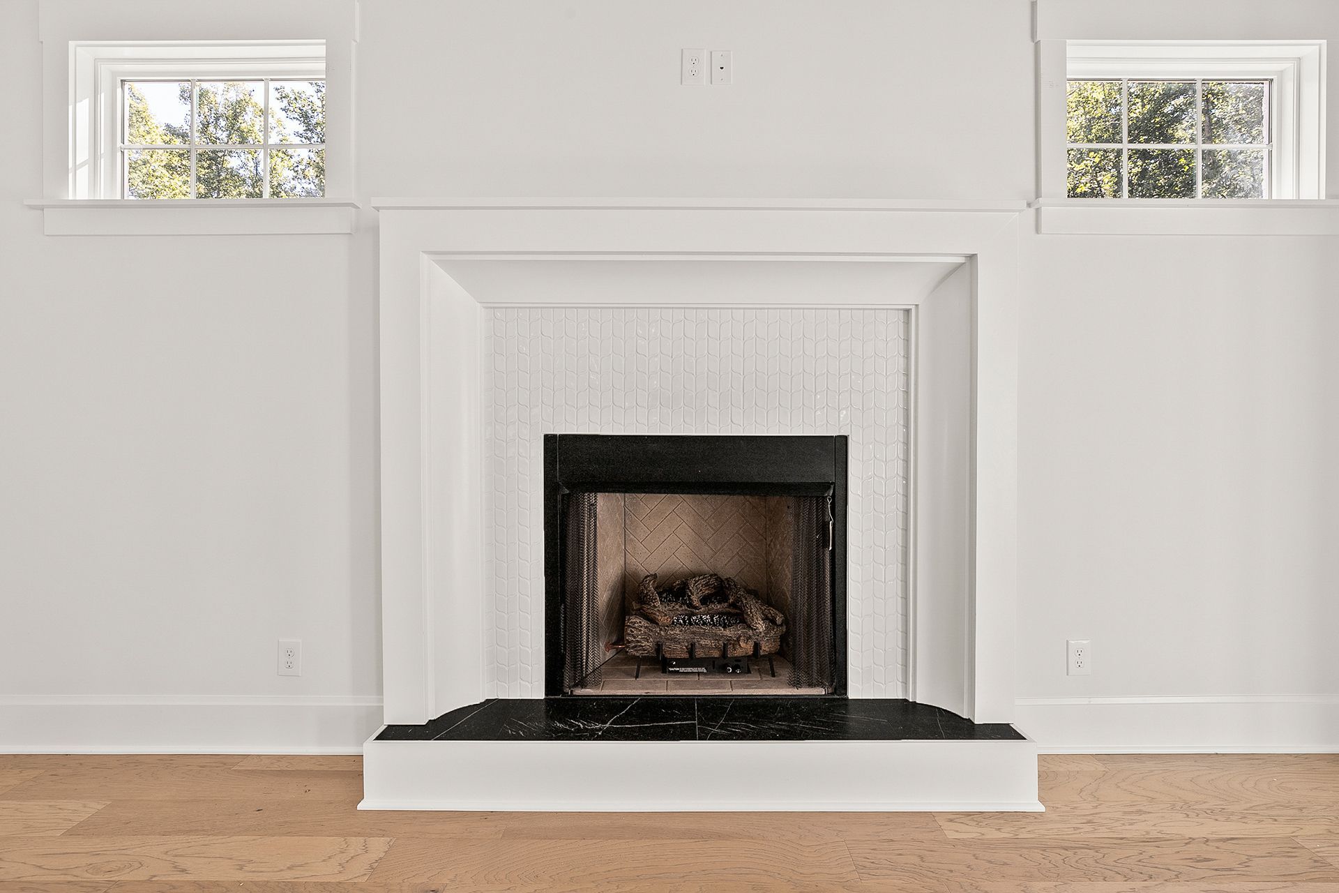 An empty living room with a fireplace and two windows