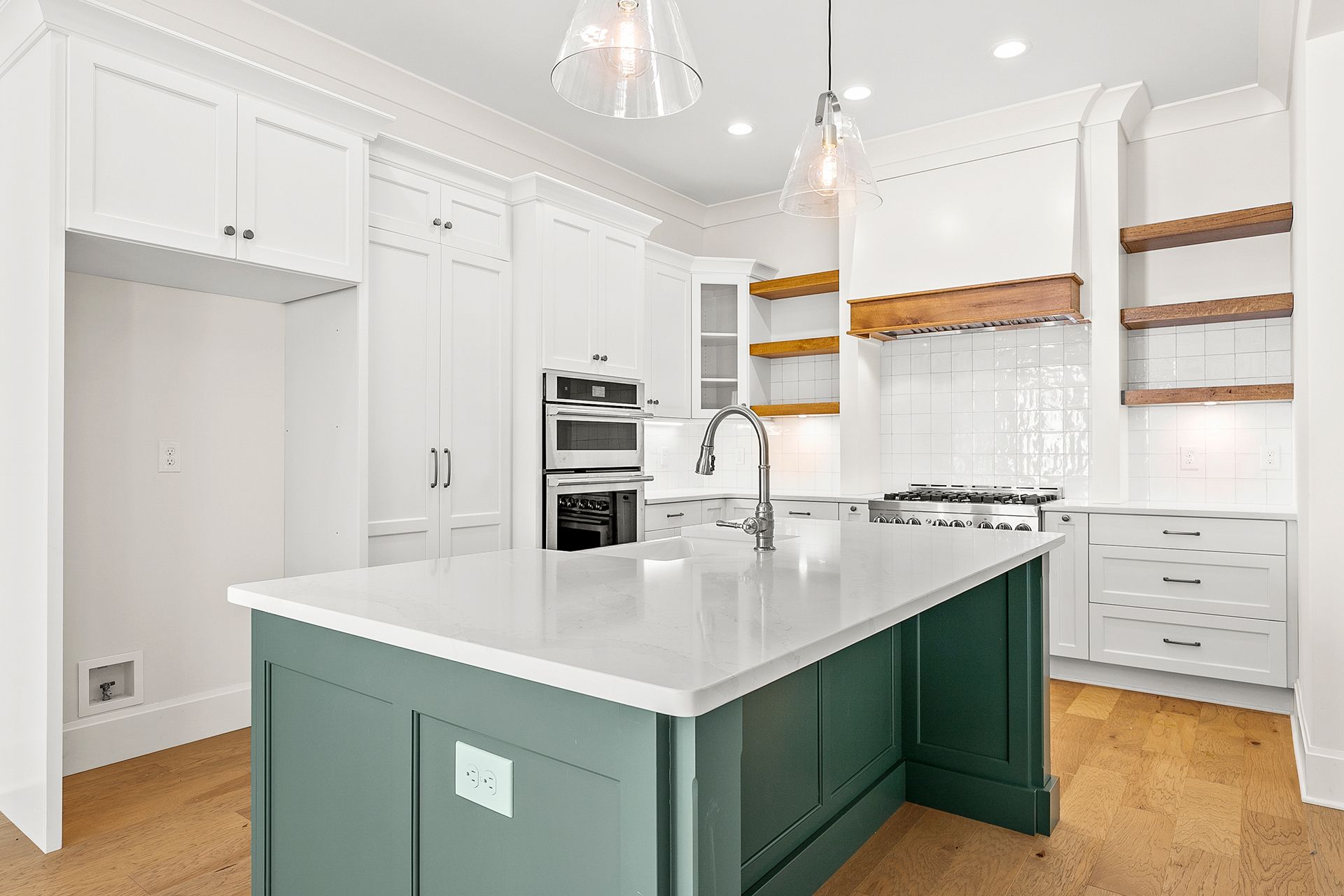 A kitchen with white cabinets and a green island