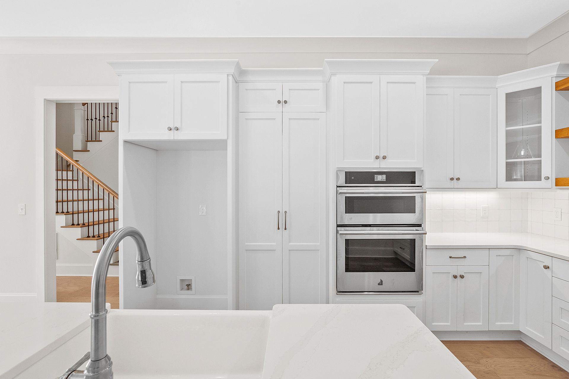 A kitchen with white cabinets, stainless steel appliances, and a sink