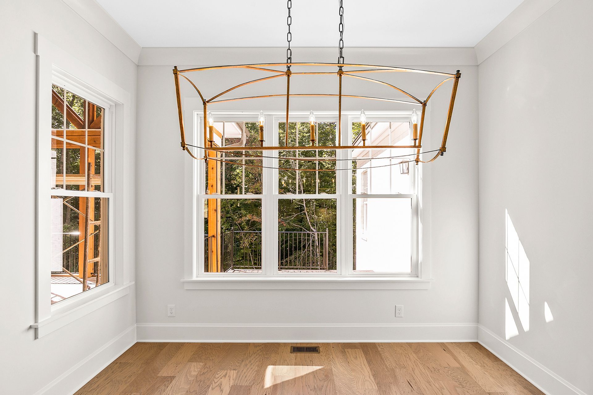 An empty room with a large window and a chandelier hanging from the ceiling
