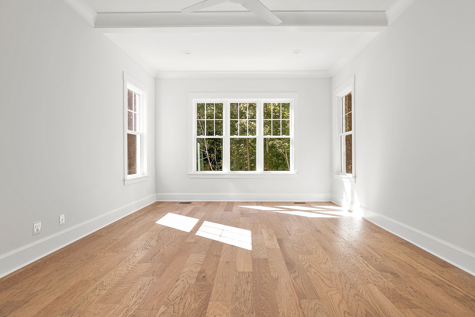 An empty room with hardwood floors and white walls