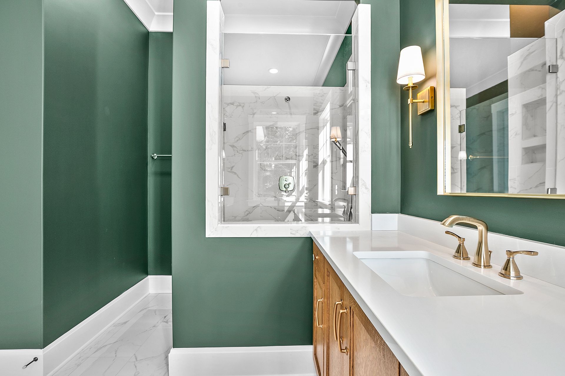 A bathroom with green walls, a sink, a mirror, and a walk-in shower
