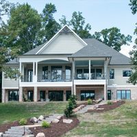 A large house is sitting on top of a hill surrounded by trees