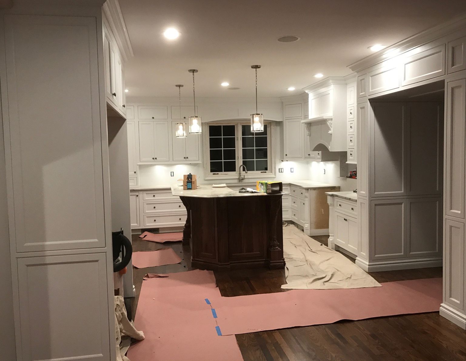 A kitchen with white cabinets and a large island in the middle