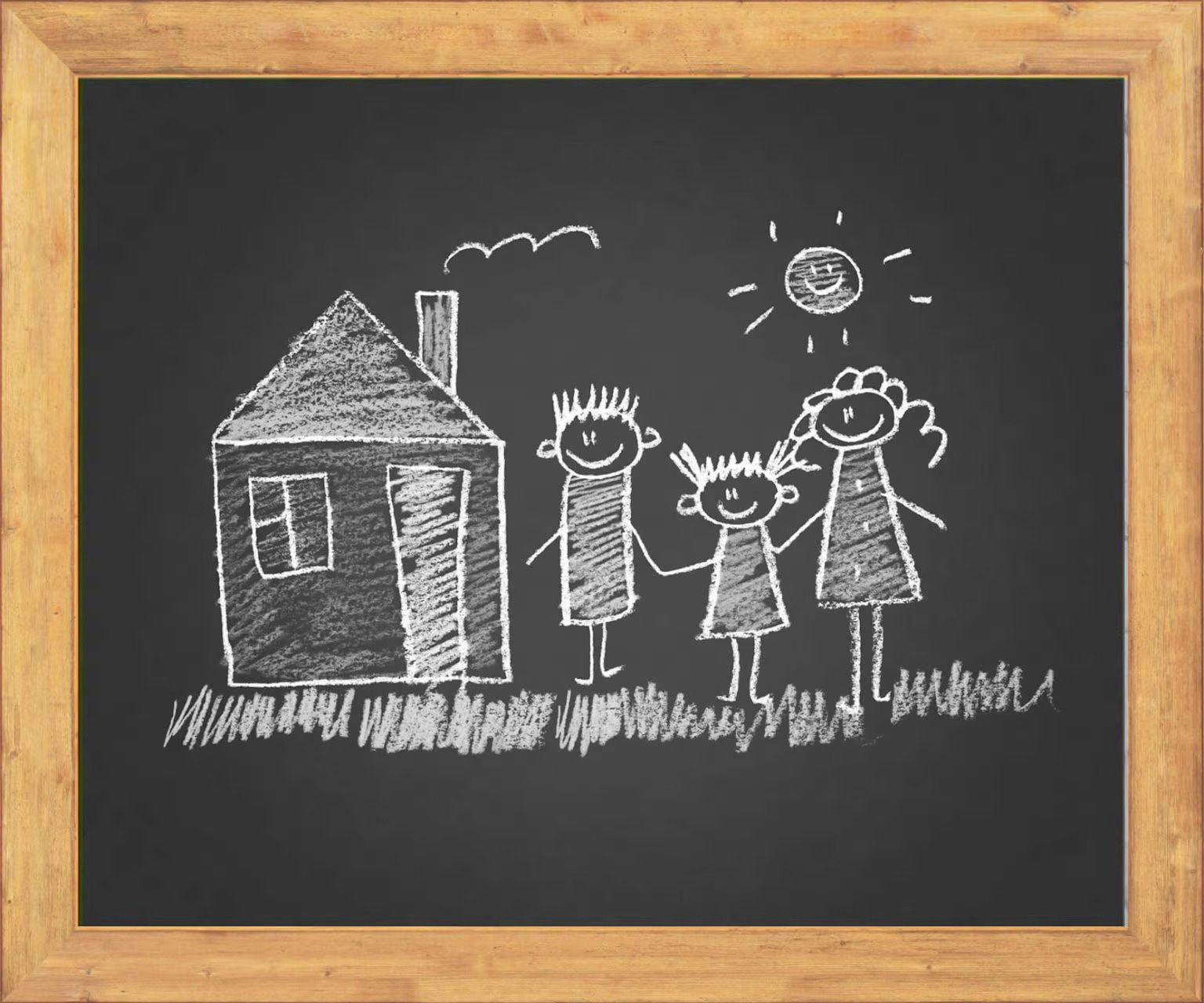 Chalk drawing on a black board showing a house, a sun, and three stick figures holding hands on a grassy field.