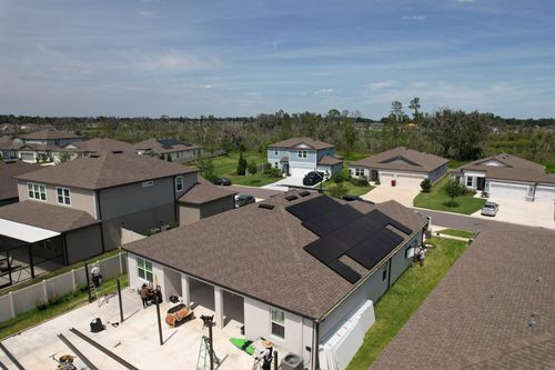 Suburban neighborhood with rows of houses, patios, and green lawns under a cloudy sky