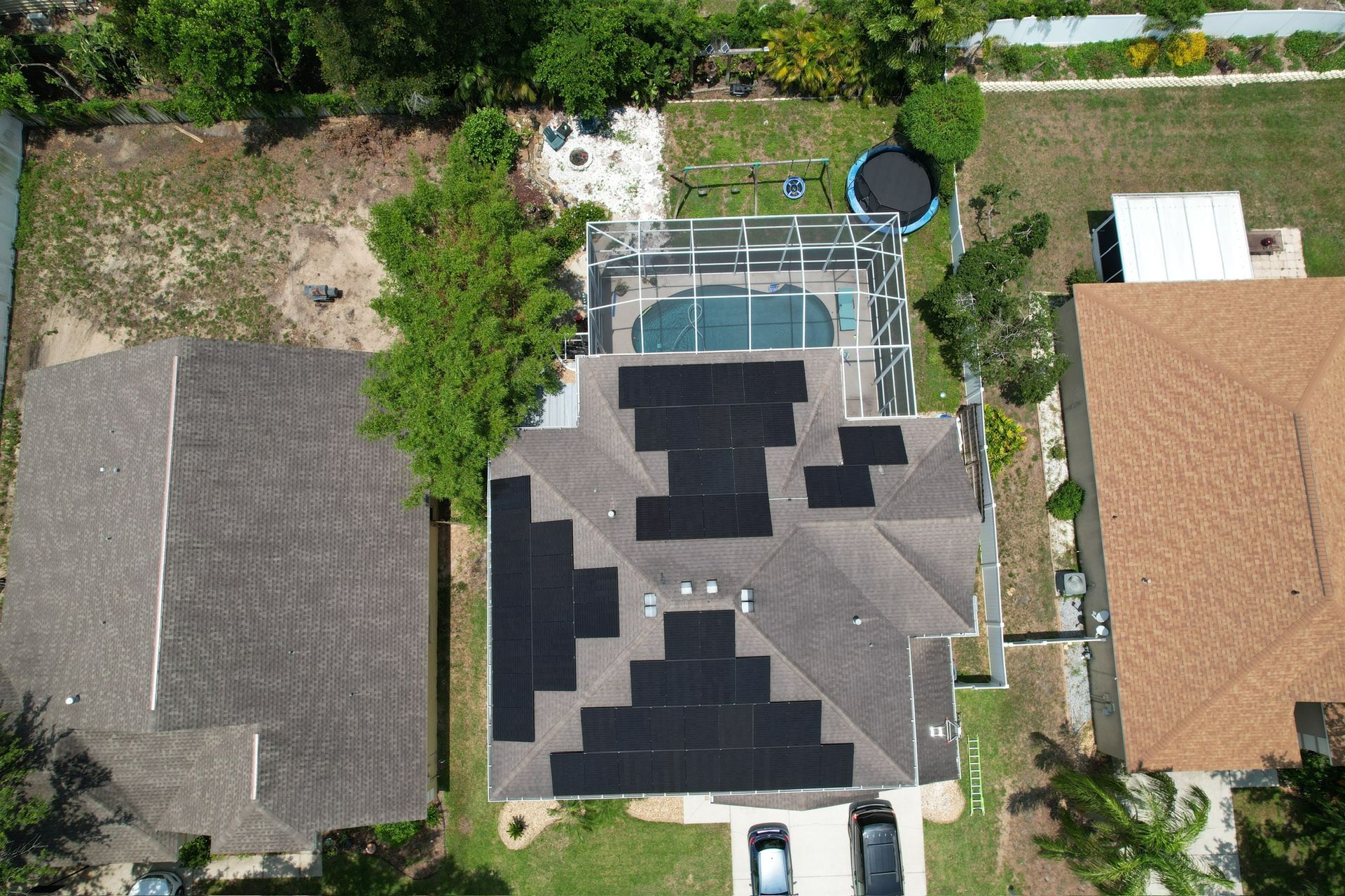Aerial view of suburban homes with a central house, backyard pool, and surrounding trees.