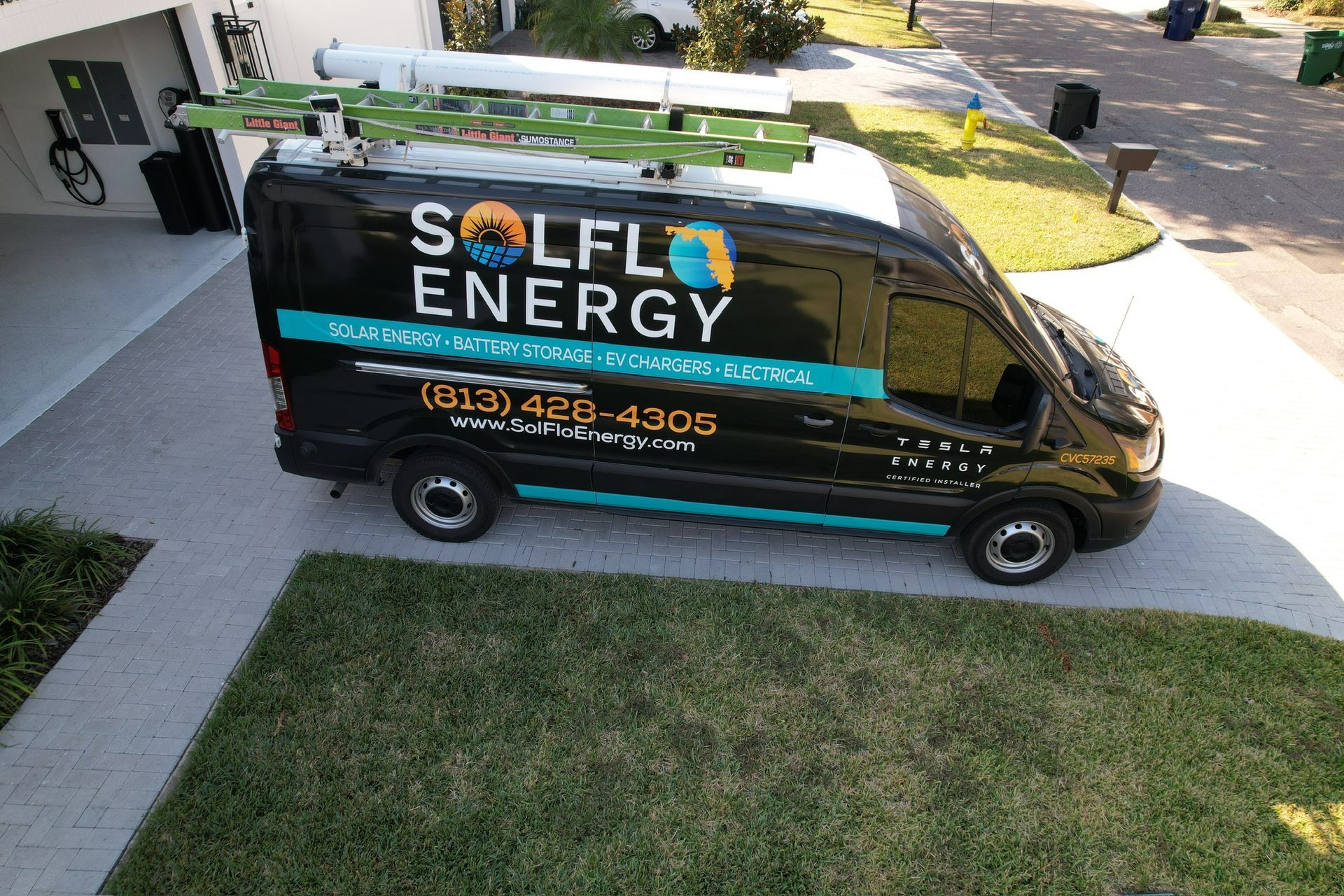 Black SOLEL ENERGY service van parked in a driveway beside a lawn and home entrance.