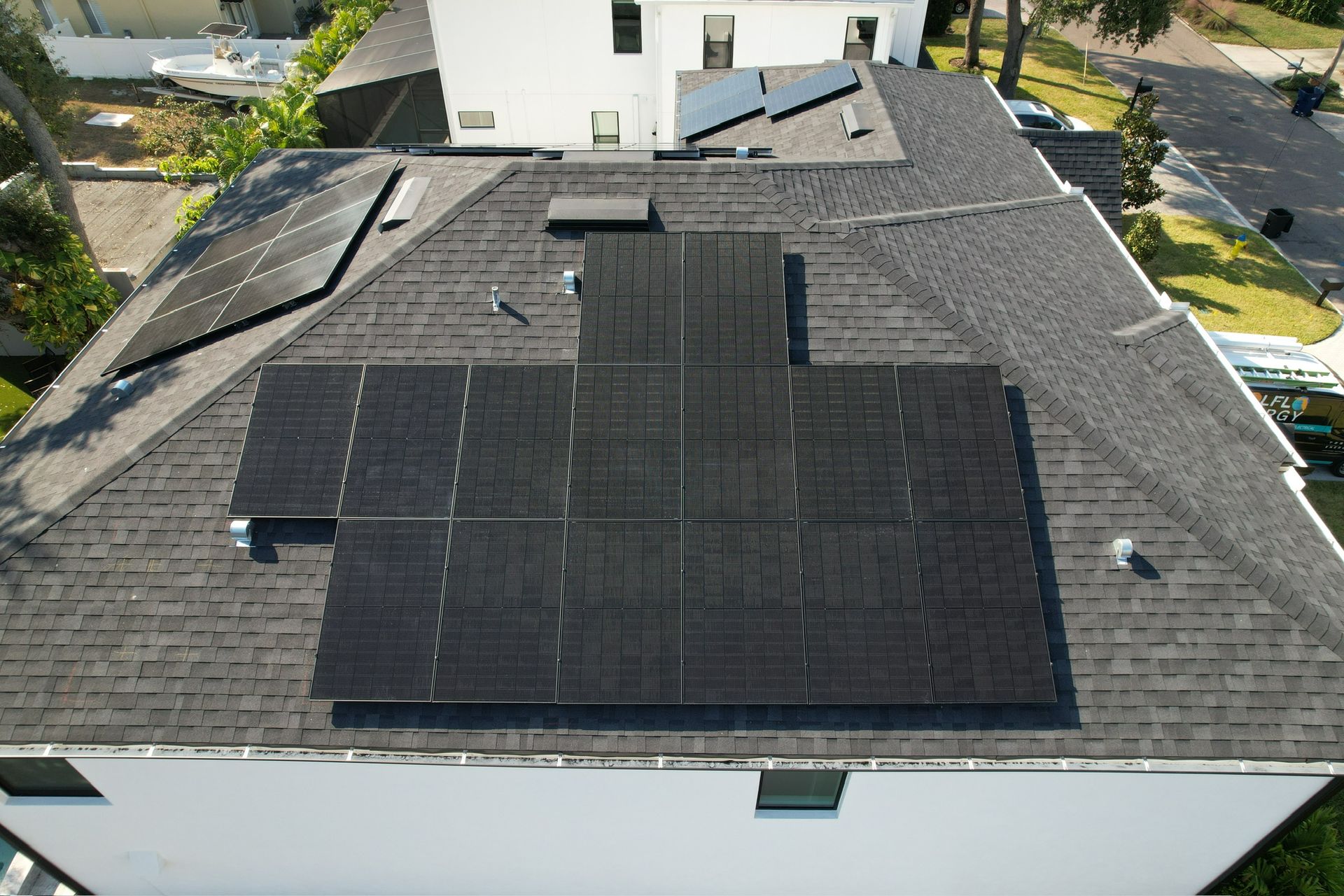Aerial view of a white house roof with large black solar panel array.