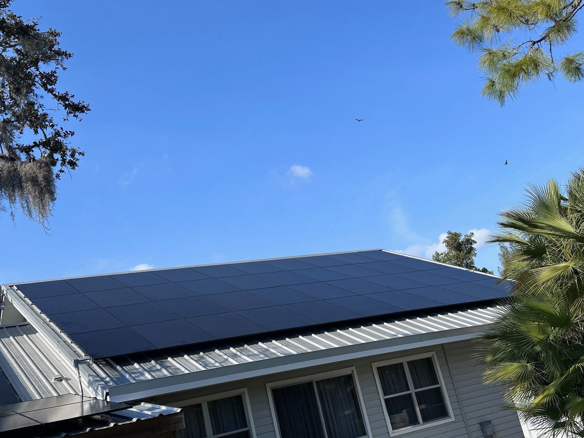 Solar panels on a house roof under a clear blue sky.