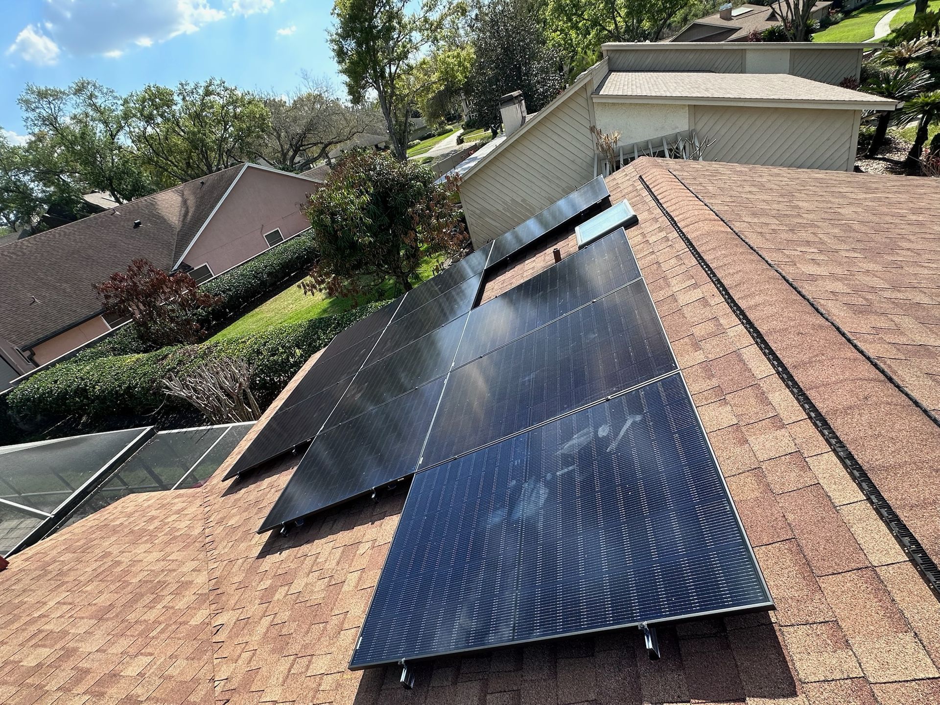 Solar panels installed on a sloped shingle roof in a residential neighborhood.