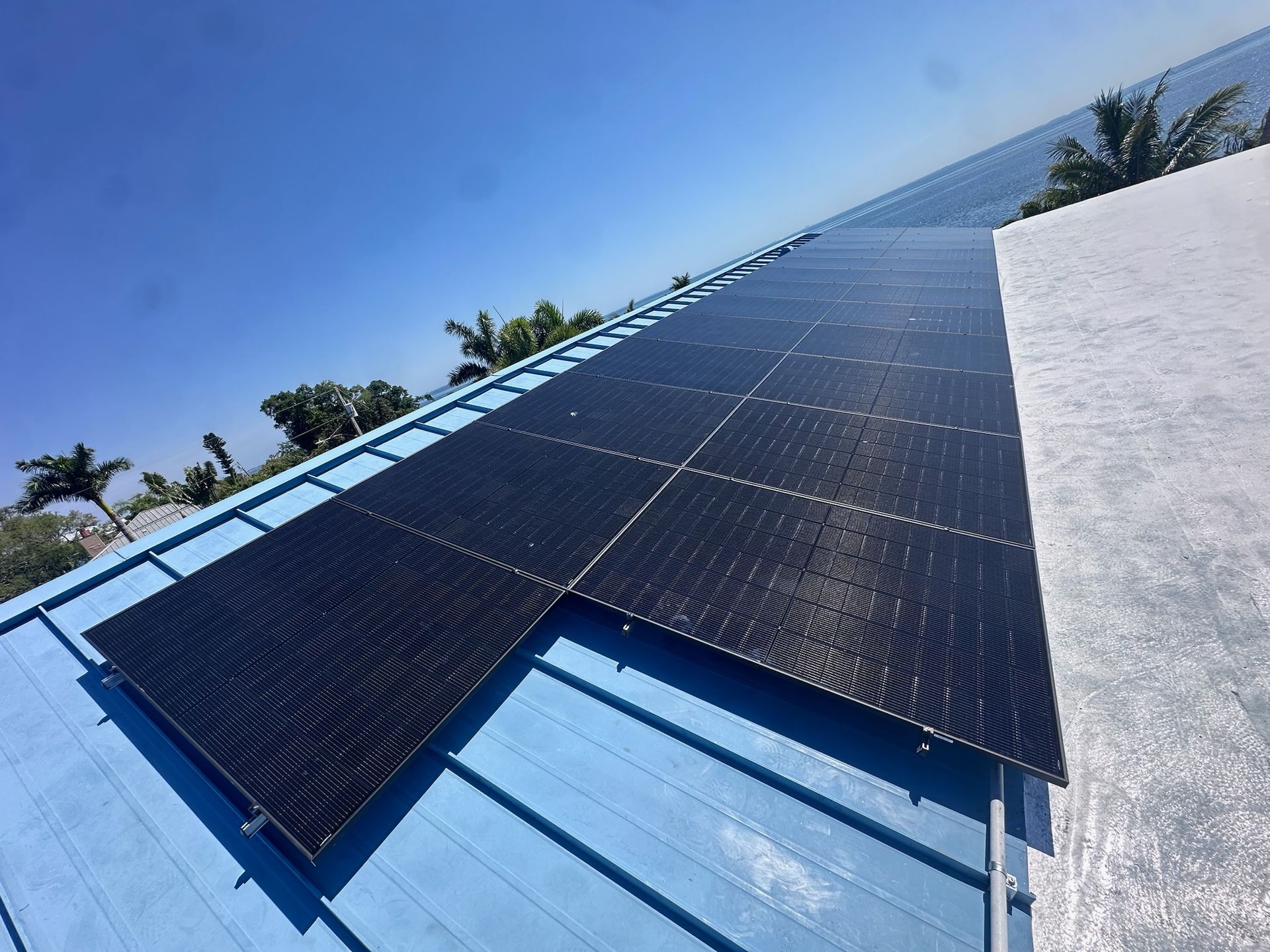 Solar panels installed on a blue rooftop under a clear sky.