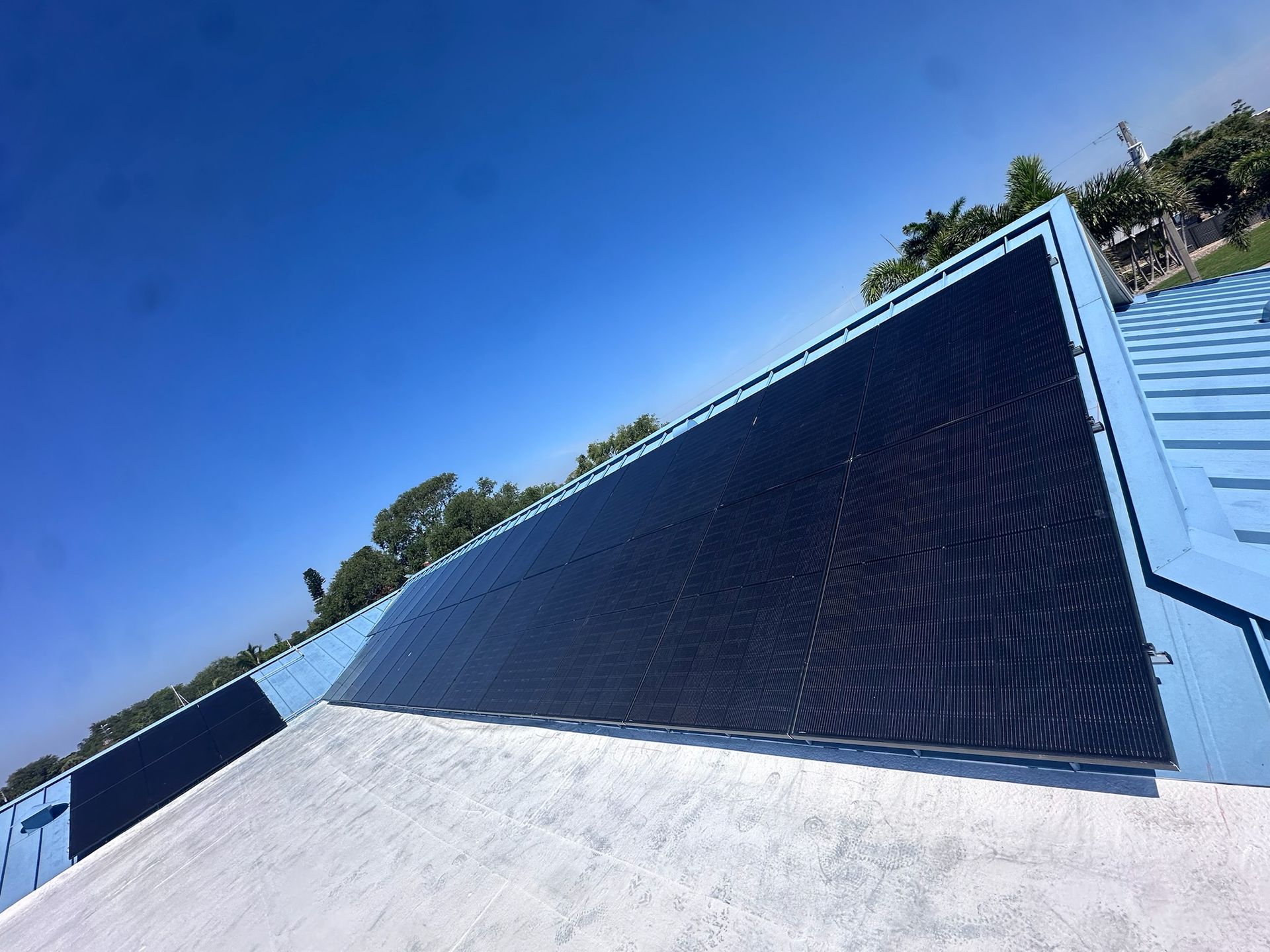 Large dark-blue solar panel array on a rooftop under a clear blue sky.