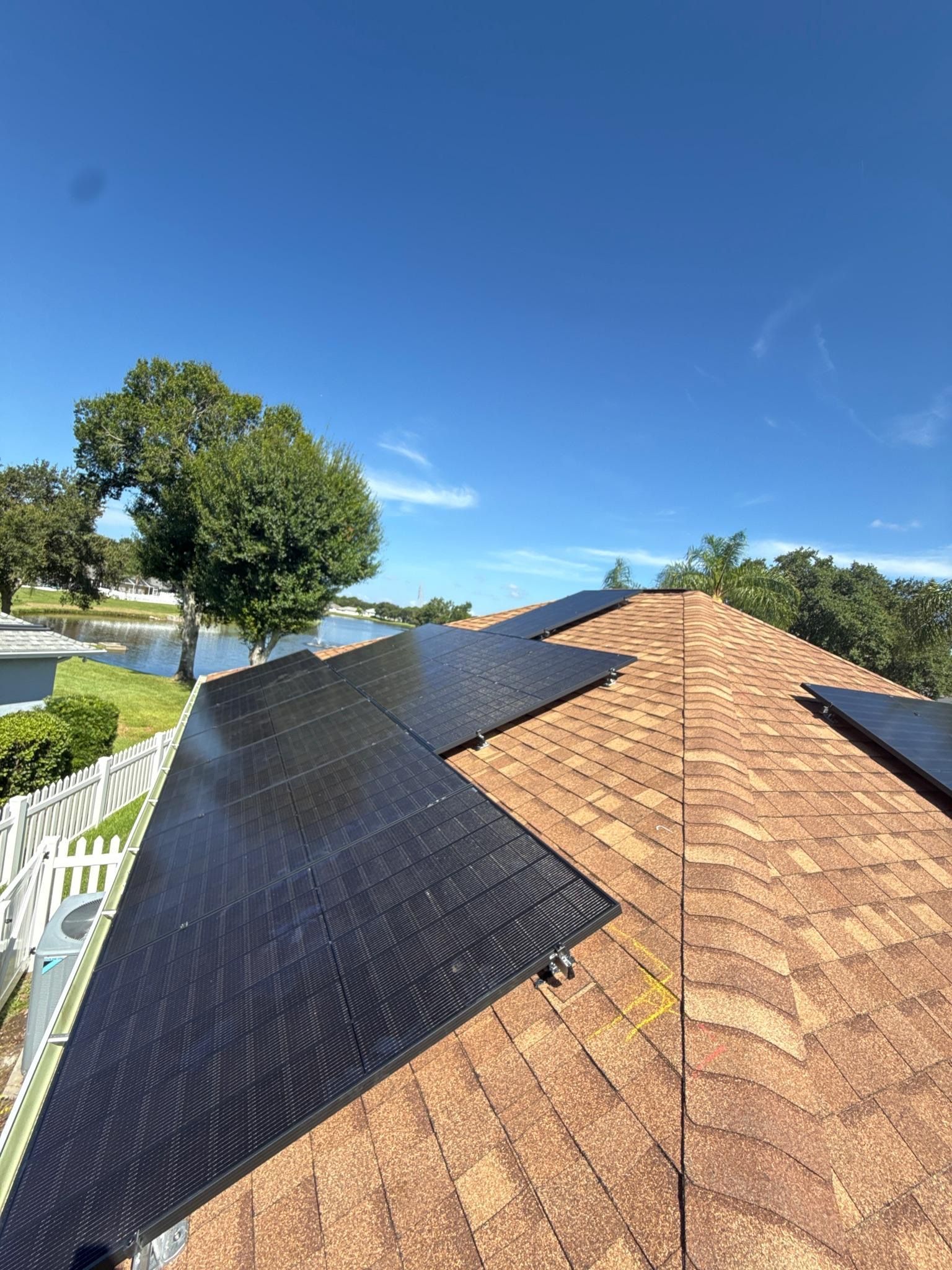 Black roof under repair with underlayment on a suburban house under a clear blue sky.