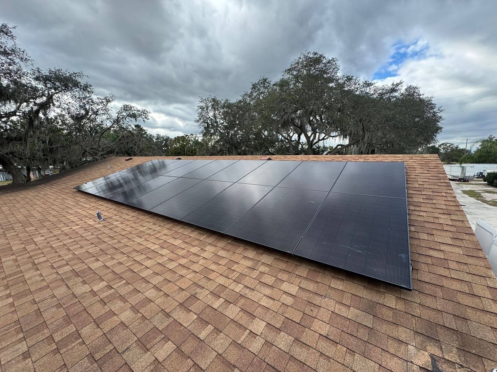 Rooftop solar panels installed on a shingled roof under a cloudy sky.