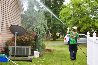 A man is cleaning the side of a house with a high pressure washer.