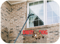 Cleaning a window on a brick house.