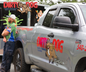 Two men are standing next to a dirty dog truck.