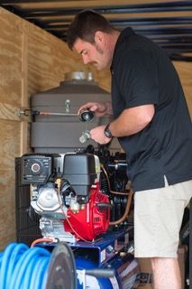 A man is working on an air compressor in a trailer.