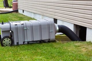 A vacuum cleaner is sitting in the grass next to a house.
