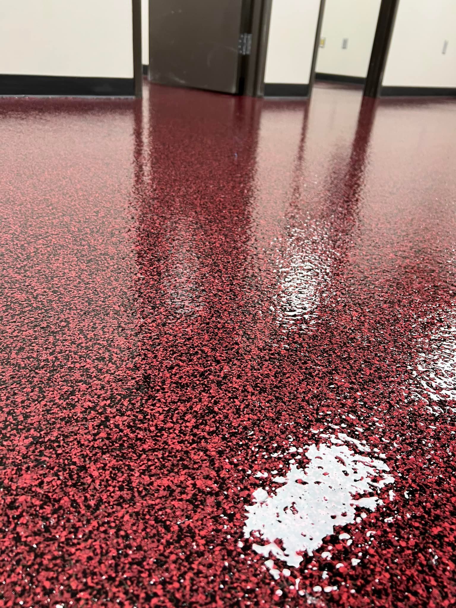 A newly coated red and black floor with a door in the background