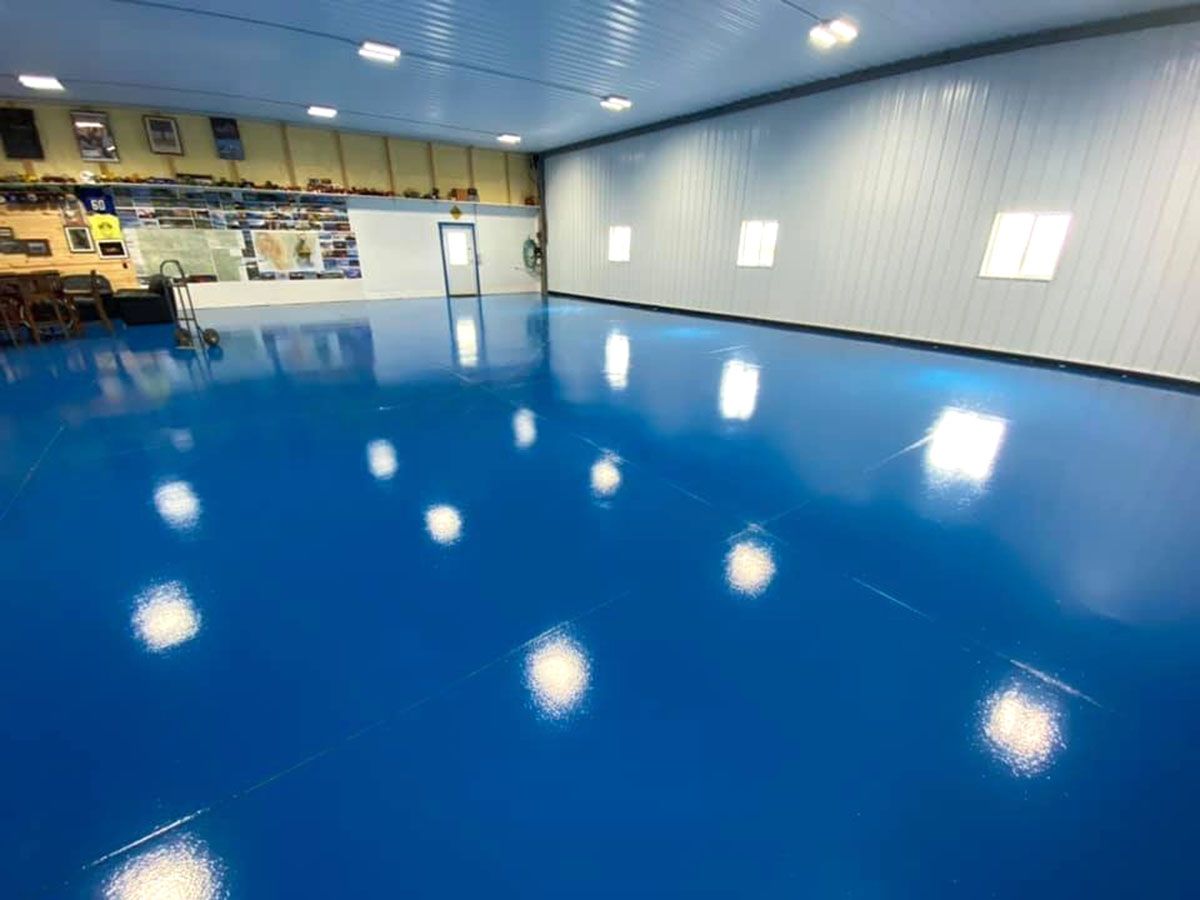 A large room with a  newly coated blue floor and white walls