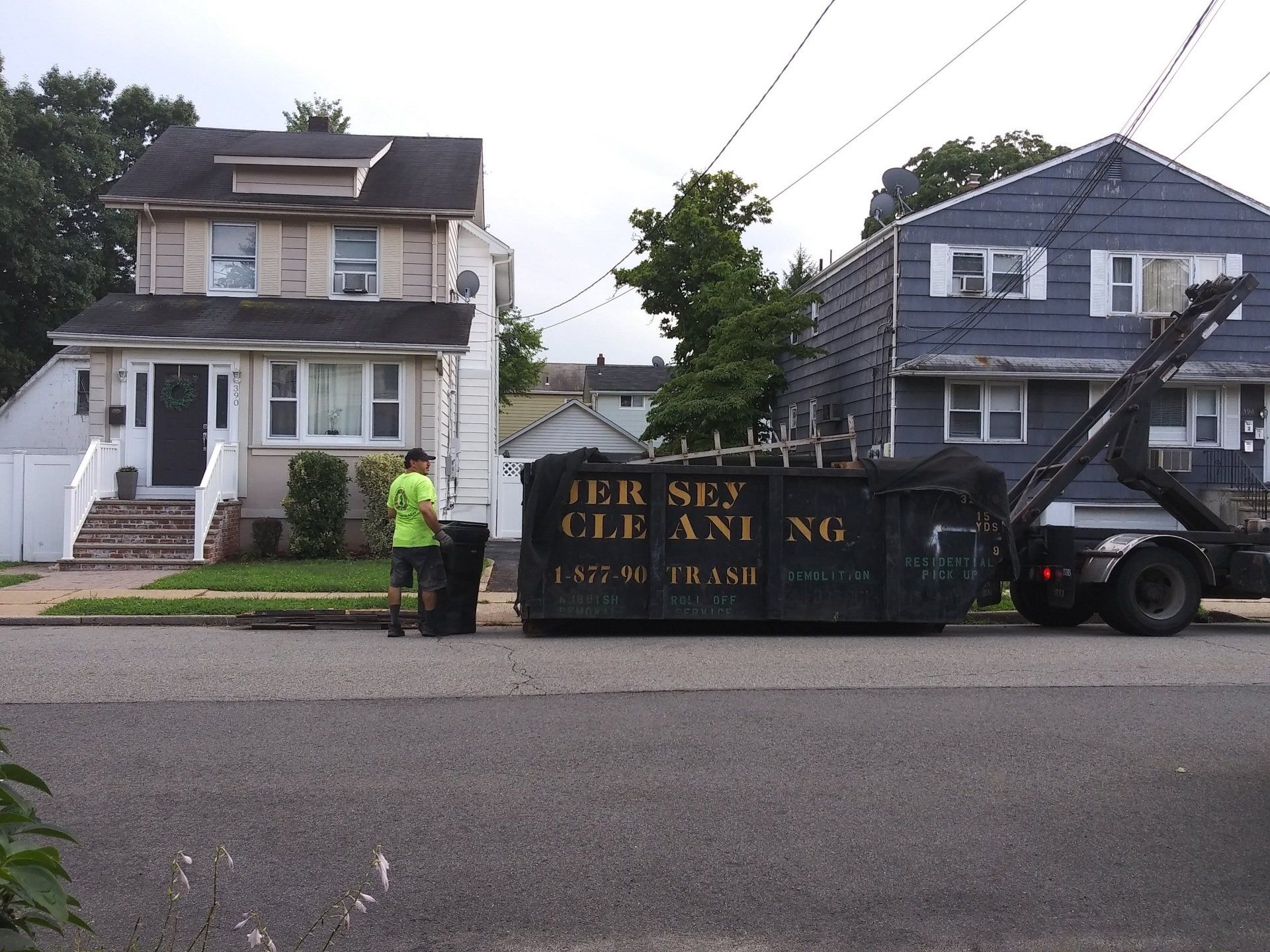 A man standing next to a black dumpster that says Jersey Cleaning.