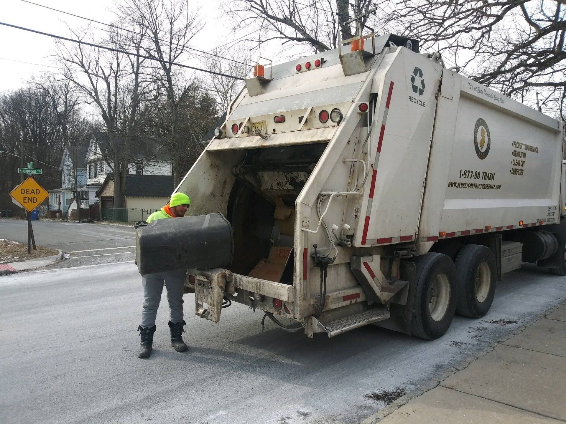 A garbage truck is parked on the side of the road.