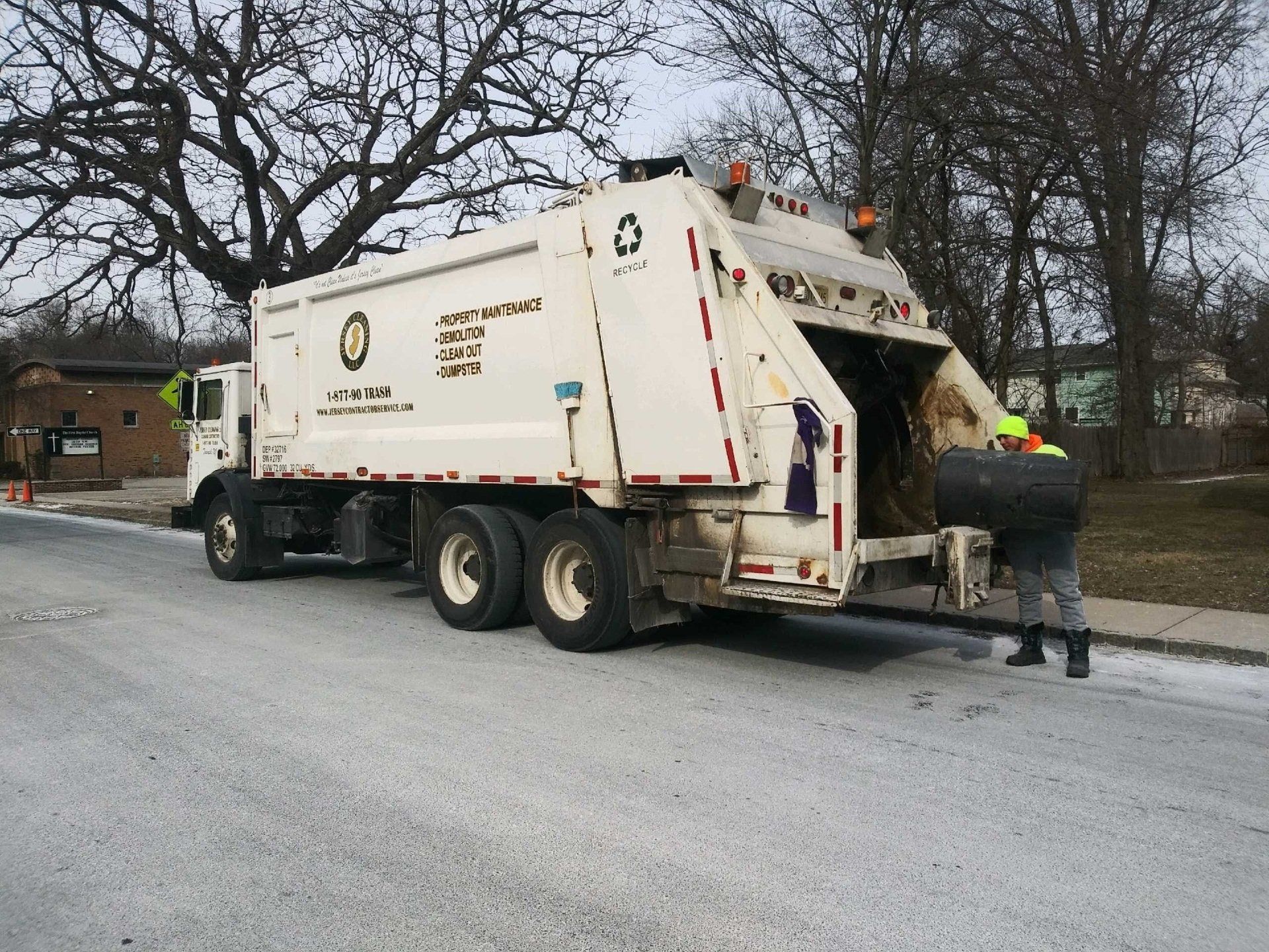 A man standing next to a black dumpster that says Jersey Cleaning.
