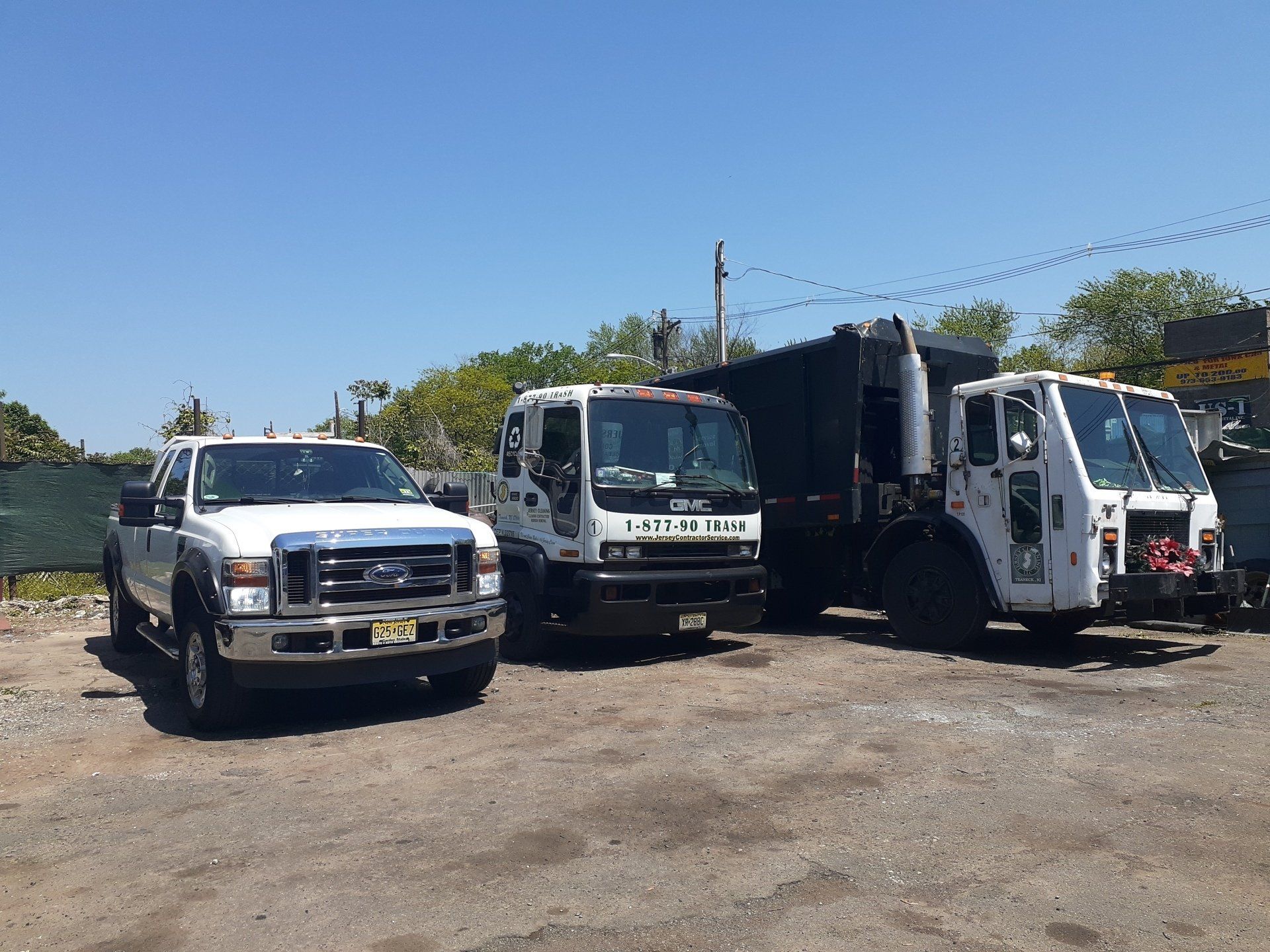 Three garbage trucks are parked in a parking lot