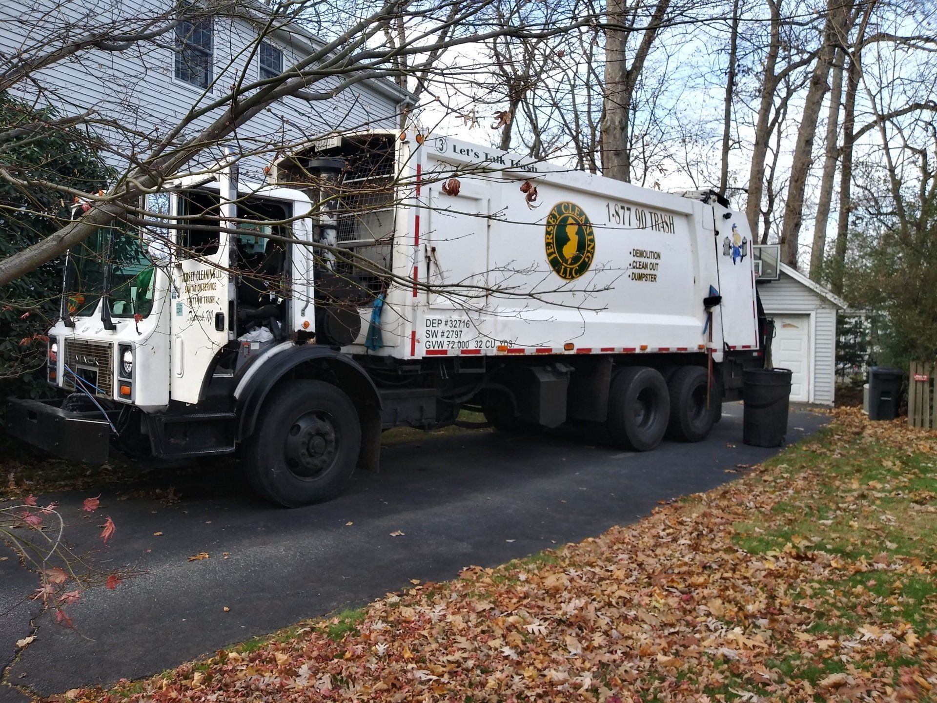 A garbage truck is parked in front of a house.