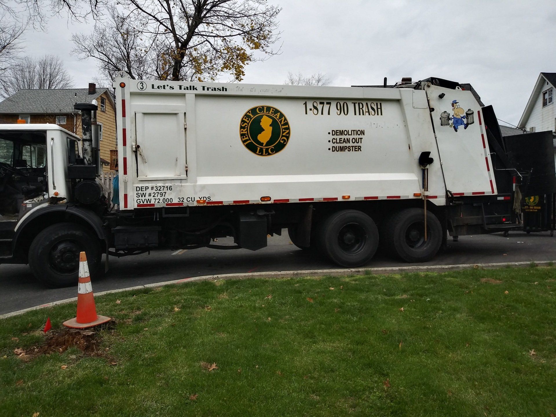 A garbage truck is parked on the side of the road.