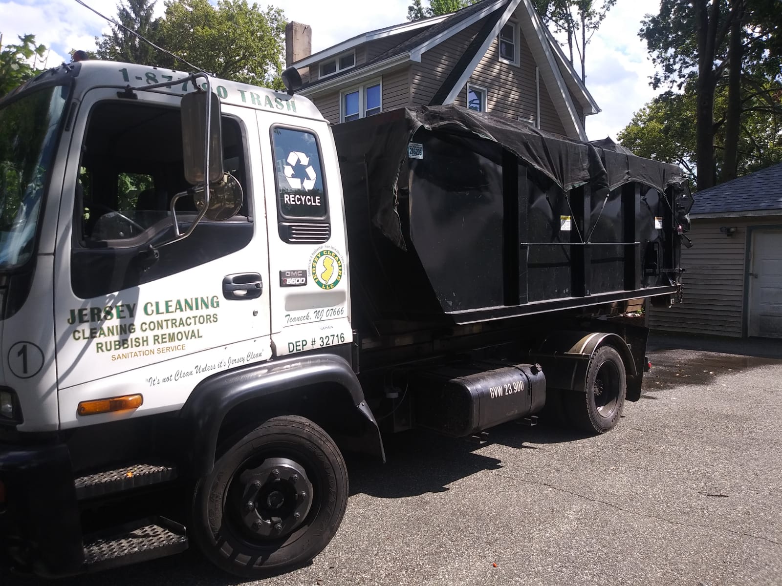 A dumpster truck is parked in front of a house