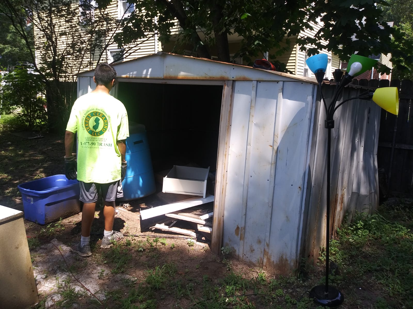 A man in a green shirt is standing in front of a shed
