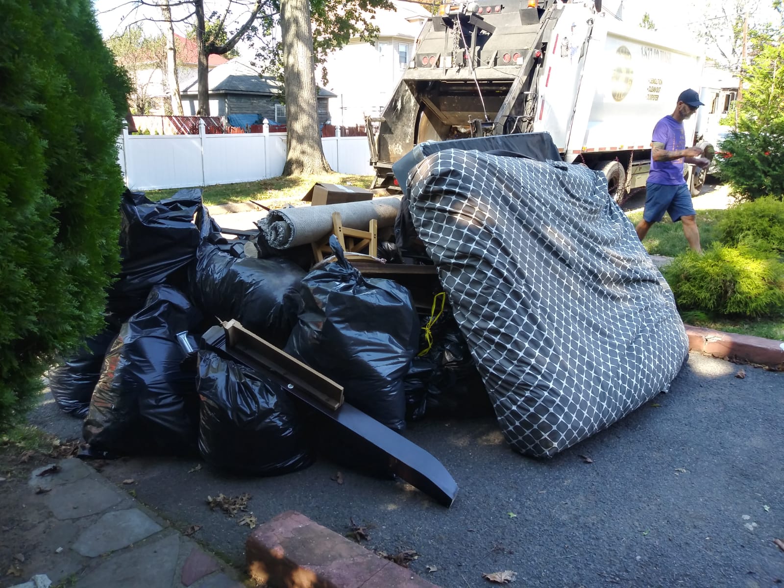 A Jersey Cleaning staff standing next to a pile of garbage bags.