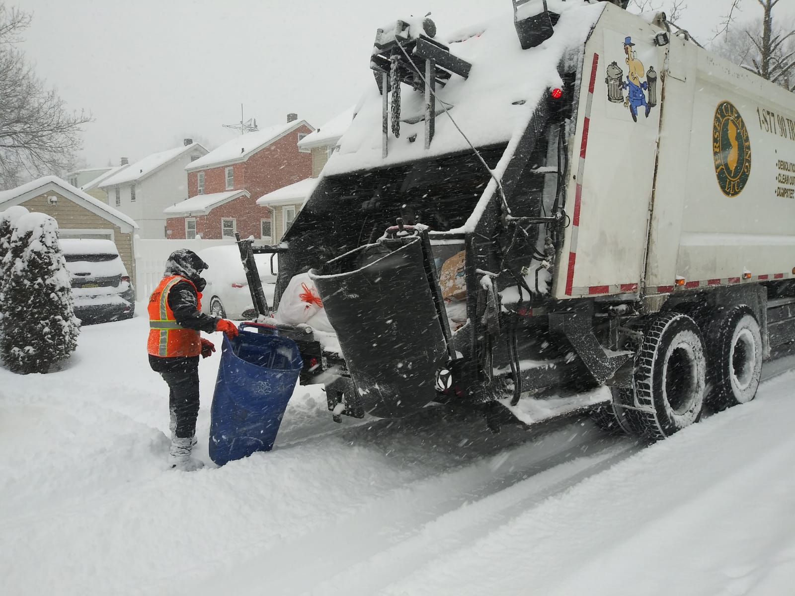 A garbage truck is being loaded with garbage in the snow