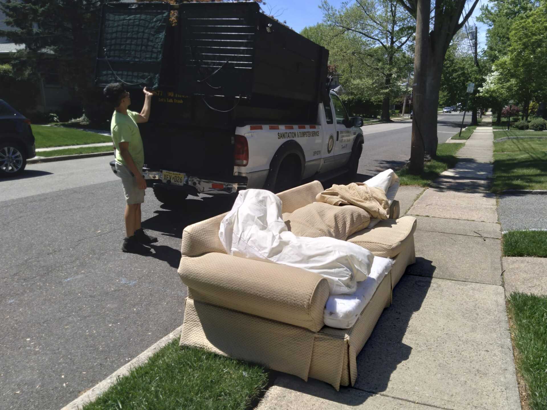 A man is loading a couch into the back of a truck