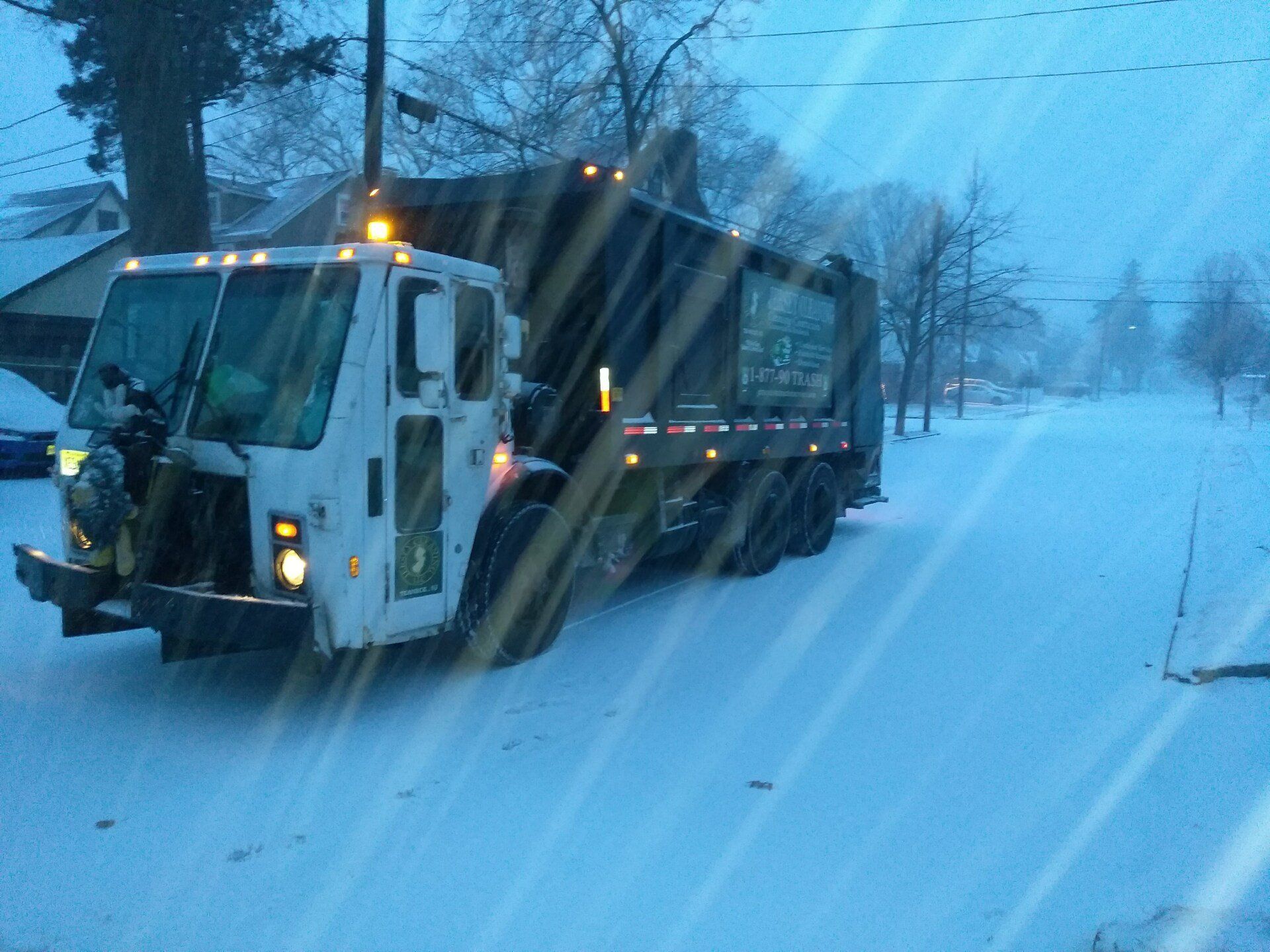 A Jersey Cleaning garbage truck is driving down a snowy street.