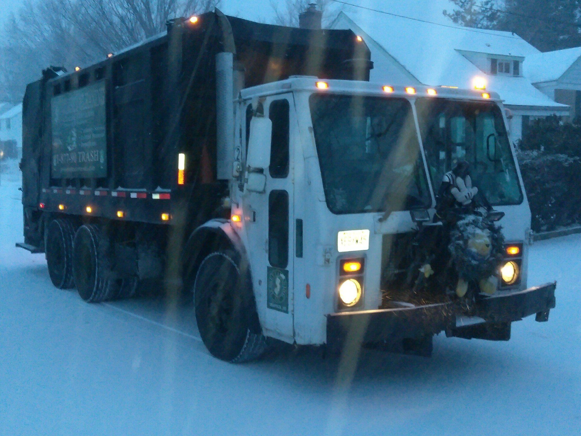 A garbage from Jersey Cleaning truck is driving down a snowy street.